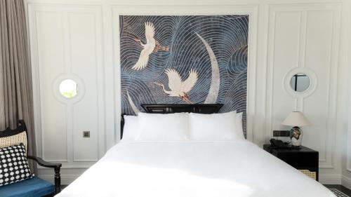 a bedroom with a white bed and a painting of birds at The City Boutique Hotel in Bien Hoa