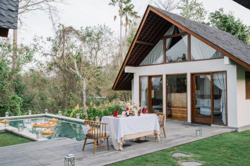 a dining table on a deck next to a pool at Arpana Luxury Private Pool Villas in Jimbaran