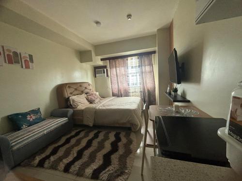 een kleine kamer met een bed en een bank bij Cozy and Affordable Studio Unit in Cebu City