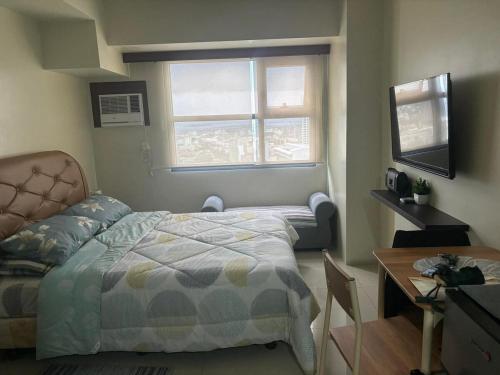 een slaapkamer met een bed, een bureau en een raam bij Cozy and Affordable Studio Unit in Cebu City