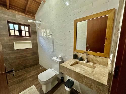 a bathroom with a toilet and a sink and a mirror at 1Km Beach Curral Air-conditioning Nos 5 Bedrooms in Ilhabela