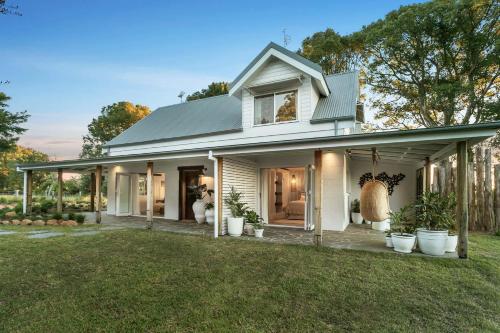 a white house with potted plants in a yard at Meadows Estate in Bangalow