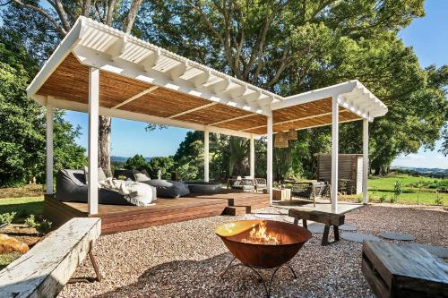 a wooden pergola with a fire pit in a yard at Meadows Estate in Bangalow