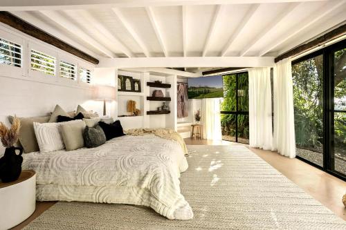 a bedroom with a large bed and a large window at Meadows Estate in Bangalow