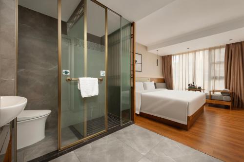 a bathroom with a shower and a bed and a sink at Fanyuan Hotel Zhujiang New City Guangzhou in Guangzhou