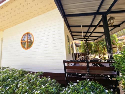 a porch with a bench on the side of a house at Baan suan khun ta บ้านพักสวนคุณตา in Ko Chang