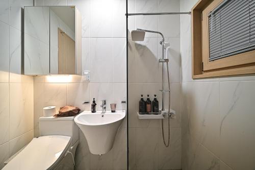 a bathroom with a shower and a sink and a toilet at Masion Sanbang Jeju in Seogwipo
