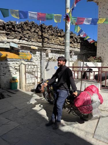 a man standing next to a motorcycle with luggage at Butterfly Lodge in Pokhara