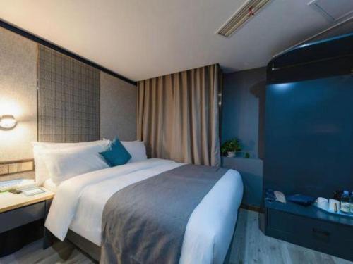a hotel room with a large bed and a desk at LANO Hotel Shandong Qingdao Jimo District Baolong Square in Qingdao