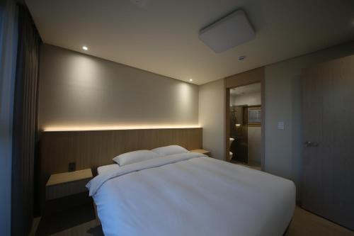a bedroom with a large white bed in it at Masion Sanbang Jeju in Seogwipo