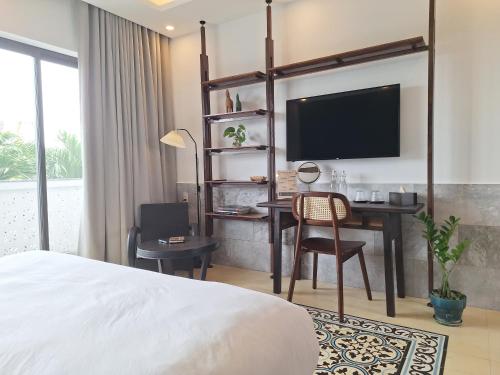 a bedroom with a bed and a desk with a television at The Interlude Art Retreat in Hoi An