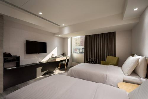 a hotel room with two beds and a desk and a television at D D Hotel in Tainan
