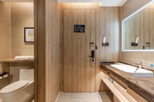 a bathroom with a sink and a toilet and a mirror at GreenTree Eastern Hotel Bengbu Huaishang District Yubo Garden in Bengbu