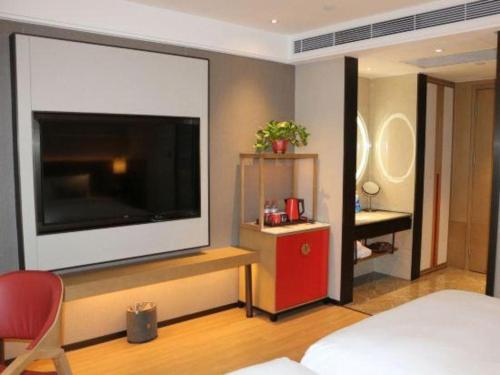 a bedroom with a large flat screen tv on a wall at E-Cheng Hotel Shenyang North Railway Station in Shenyang