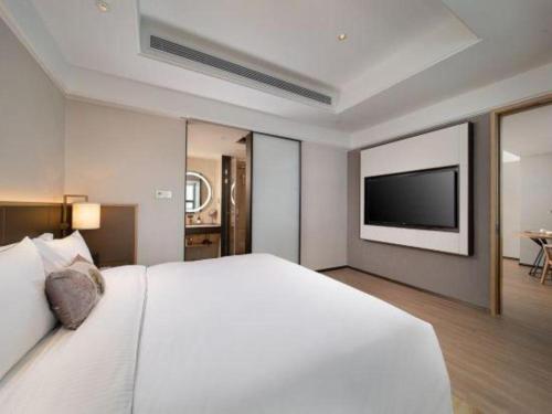 a bedroom with a large white bed and a flat screen tv at E-Cheng Hotel Shenyang North Railway Station in Shenyang