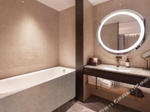 a bathroom with a bath tub and a mirror at E-Cheng Hotel Shenyang North Railway Station in Shenyang