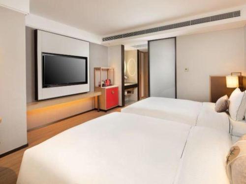 a bedroom with a large white bed and a flat screen tv at E-Cheng Hotel Shenyang North Railway Station in Shenyang