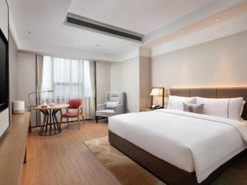 a bedroom with a large white bed and a table and chair at E-Cheng Hotel Shenyang North Railway Station in Shenyang