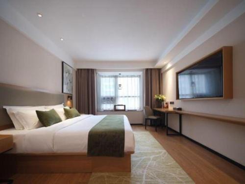 ein Hotelzimmer mit einem Bett und einem Flachbildfernseher in der Unterkunft GreenTree Inn Luoyang Railway Station Wangfujing Wangcheng Park in Luoyang