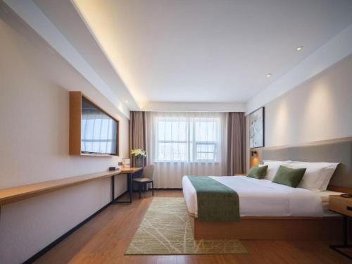 a hotel room with a bed and a desk at GreenTree Inn Luoyang Railway Station Wangfujing Wangcheng Park in Luoyang
