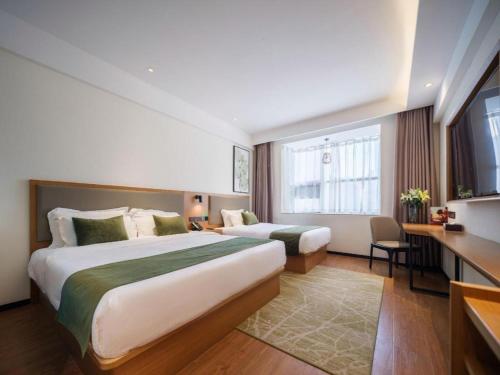 ein Hotelzimmer mit zwei Betten und einem Schreibtisch in der Unterkunft GreenTree Inn Luoyang Railway Station Wangfujing Wangcheng Park in Luoyang
