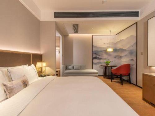 ein Schlafzimmer mit einem großen weißen Bett und einem roten Stuhl in der Unterkunft GreenTree Eastern Hotel Nanning Wuxiang Hangyang City in Nanning