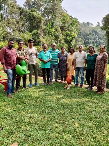 a group of people posing for a picture in the grass at ARABIAN HOLIDAY RESORT WITH SWIMMING POOL IN IDUKKI Calvary Mount in Idukki