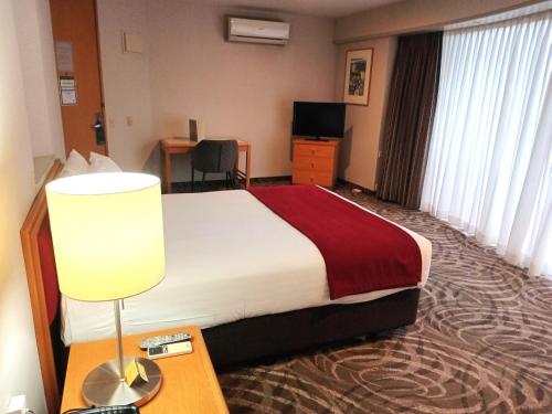 a hotel room with a large bed and a desk at Waipuna Hotel & Conference Centre in Auckland