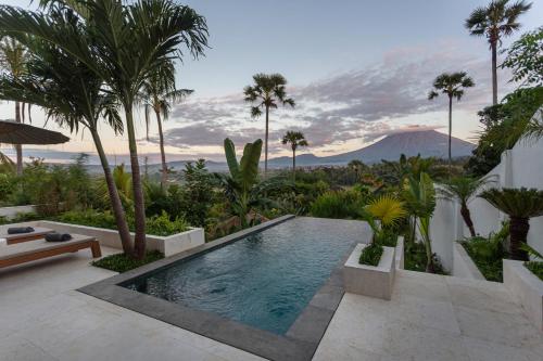 a swimming pool in the middle of a garden with palm trees at East Bali Volcano View Resort & Spa - Adults Only Area in Karangasem