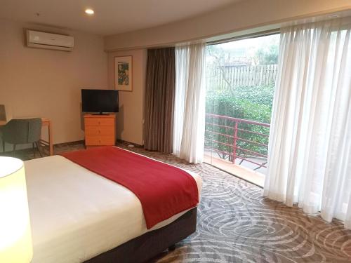 a hotel room with a bed and a large window at Waipuna Hotel & Conference Centre in Auckland