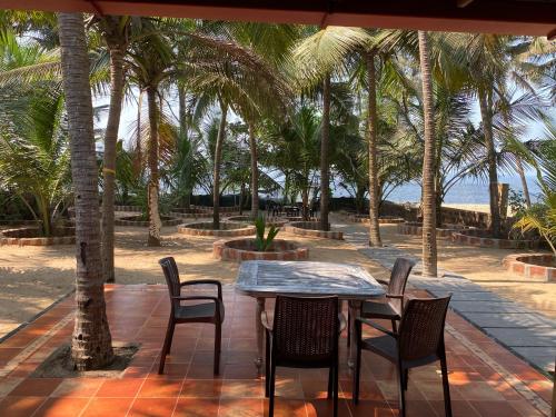 a table and chairs on a patio with palm trees at SeaEsta Beach House in Pāngāla