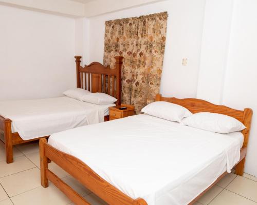 two beds in a room with white sheets at Lesville Tobago in Canaan