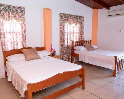 a bedroom with two beds and two windows at Lesville Tobago in Canaan