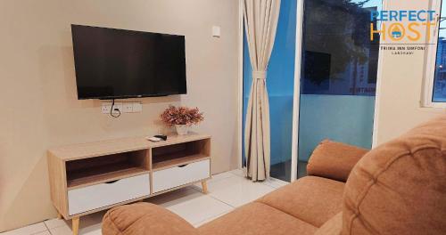 a living room with a television and a couch at Triima Inn Dayang Bay by Perfect Host in Kuah
