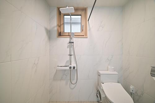 a shower in a bathroom with a toilet and a window at Masion Sanbang Jeju in Seogwipo