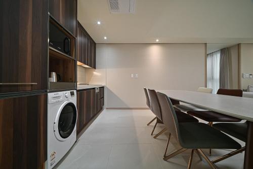 a kitchen with a table and a washing machine at Masion Sanbang Jeju in Seogwipo