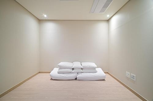 a room with three white pillows on a floor at Masion Sanbang Jeju in Seogwipo