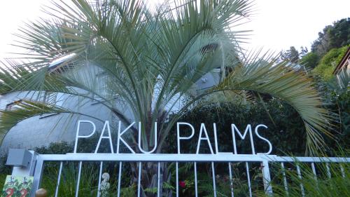 a sign in front of a palm tree at Paku Palms in Tairua