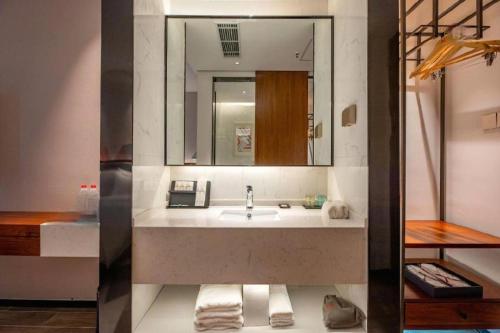 une salle de bain avec un lavabo et un miroir dans l'établissement Borrman Hotel Guilin North Railway Station Zhonghao International, à Lingchuan