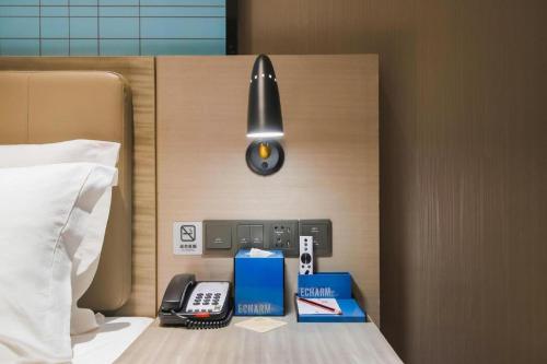 a hotel room with a bed with a phone and boxes at Echarm Hotel Changsha Wuyi Square Xiangya Affiliated 1st Provincial Maternity and Child in Changsha