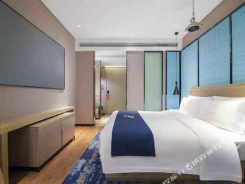 a bedroom with a large bed and a flat screen tv at Echarm Hotel Changsha Wuyi Square Xiangya Affiliated 1st Provincial Maternity and Child in Changsha