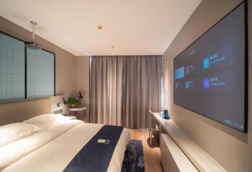 a hotel room with a large tv and a bed at Echarm Hotel Changsha Wuyi Square Xiangya Affiliated 1st Provincial Maternity and Child in Changsha