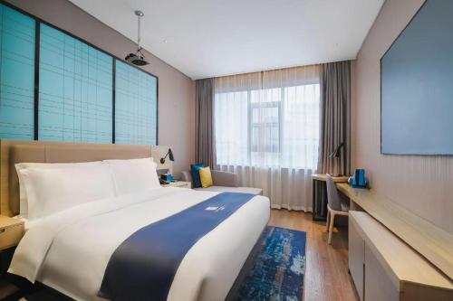 a hotel room with a large bed and a screen at Echarm Hotel Changsha Wuyi Square Xiangya Affiliated 1st Provincial Maternity and Child in Changsha