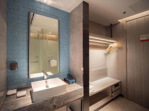 a bathroom with a sink and a mirror at Echarm Hotel Changsha Wuyi Square Xiangya Affiliated 1st Provincial Maternity and Child in Changsha