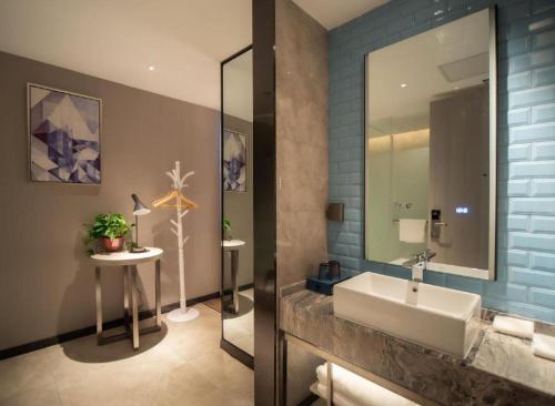 a bathroom with a sink and a mirror at Echarm Hotel Changsha Wuyi Square Xiangya Affiliated 1st Provincial Maternity and Child in Changsha