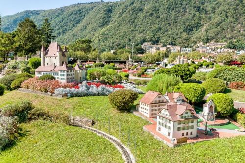 a small town with houses and a train on a hill at Residenza Lungolago Melide - Happy Rentals in Melide