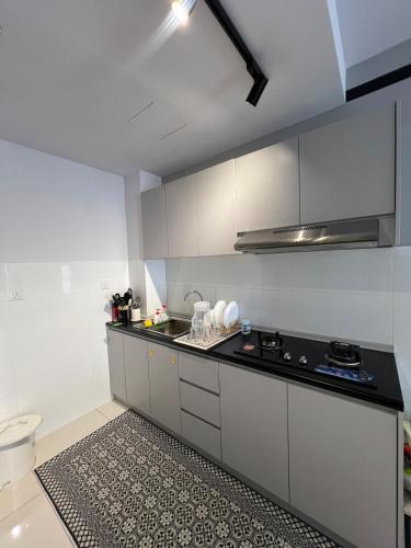 a kitchen with white cabinets and a black counter top at Hafiz Homestay Gaia Residence Mus Lim Only in Rawang