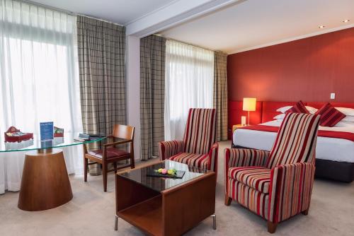 a hotel room with a bed and a table and chairs at Waipuna Hotel & Conference Centre in Auckland
