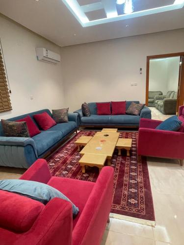 a living room with red couches and a coffee table at RoseVilla روزفيلا in Ḩaql