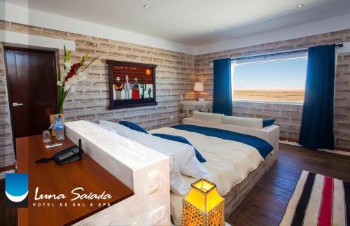 a bedroom with a large bed and a brick wall at Hotel de Sal Luna Salada in Colchani